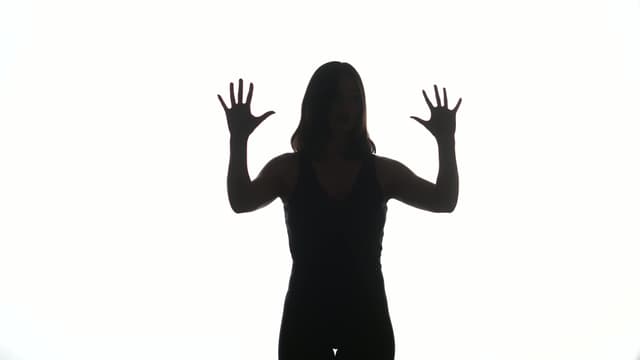 A silhoutted dancer in front of a plain white backdrop