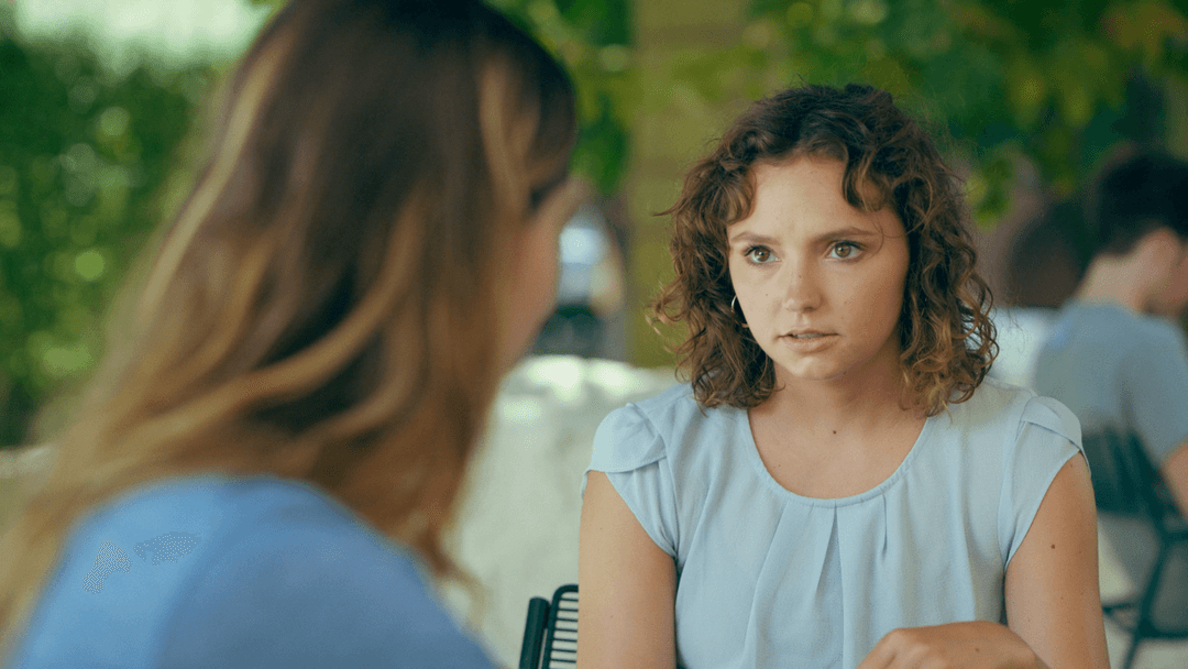 Kate and her friend talk at a cafe