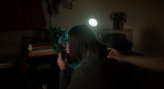 A hand reaches out to someone looking in a mirror