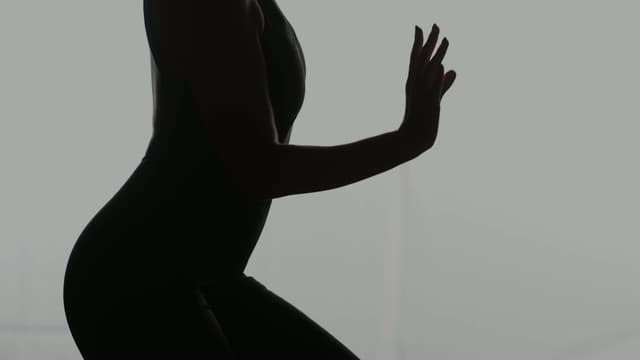 A silhoutted dancer in front of a plain white backdrop