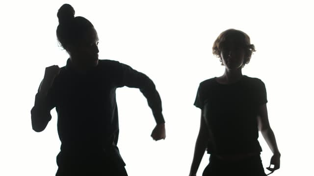 Two silhoutted dancers in front of a plain white backdrop