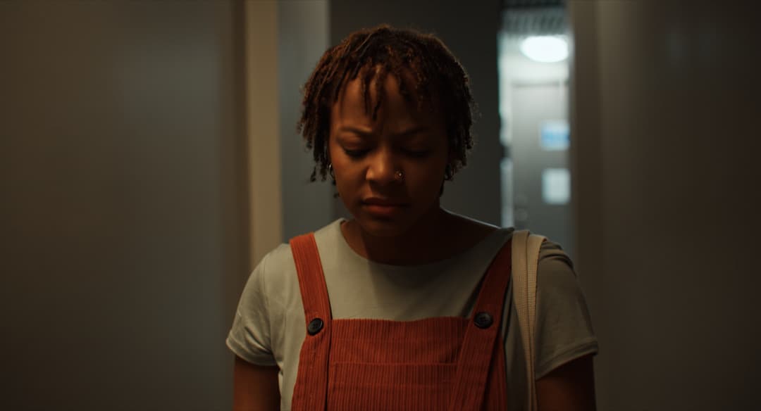 A woman in a dark hallway looks down at something