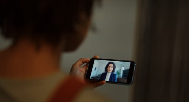 Over-the-shoulder shot of a woman watching a video on her phone