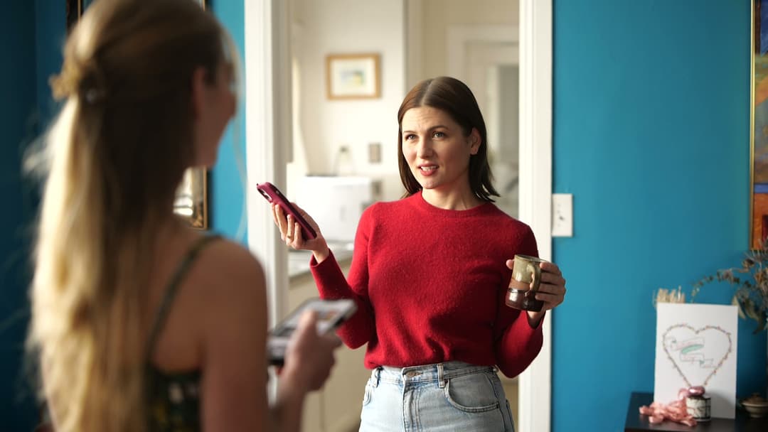 A woman talking with her friend while holding a phone