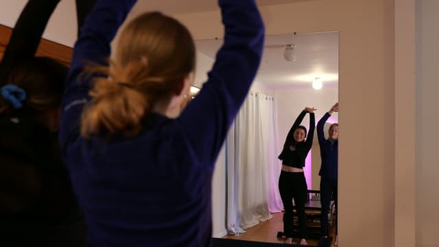 Two women doing stretches in the mirror