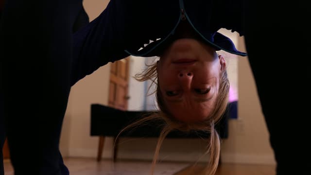 A woman's head upside-down as she touches her toes