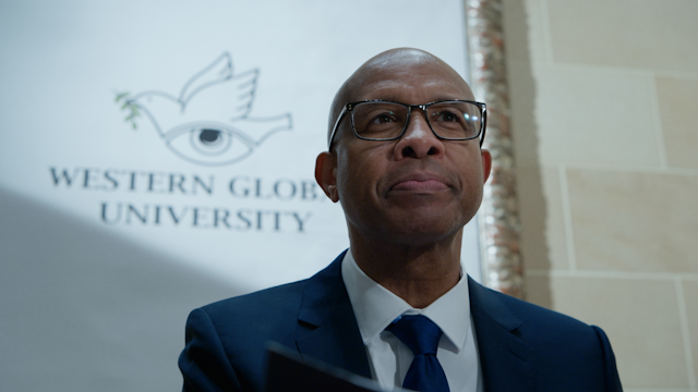Dean Butler with the logo of Western Global University behind him