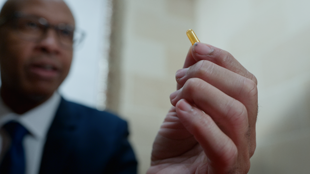 A close-up of a pill that the dean holds in his hand